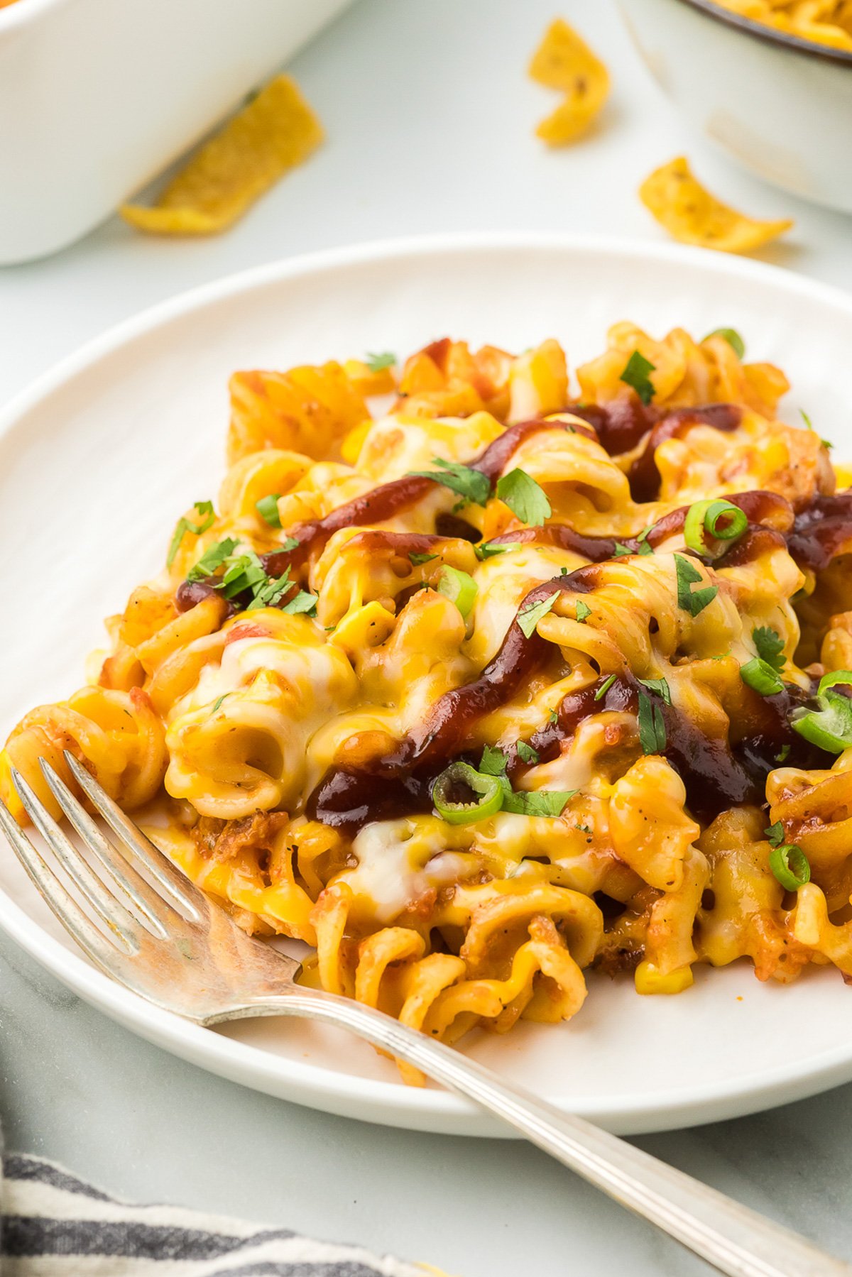 Chicken Pasta Casserole on a white plate with bbq sauce and garnish with a fork.