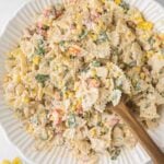 Mexican Street Corn Pasta Salad with a wooden spoon in a white bowl.