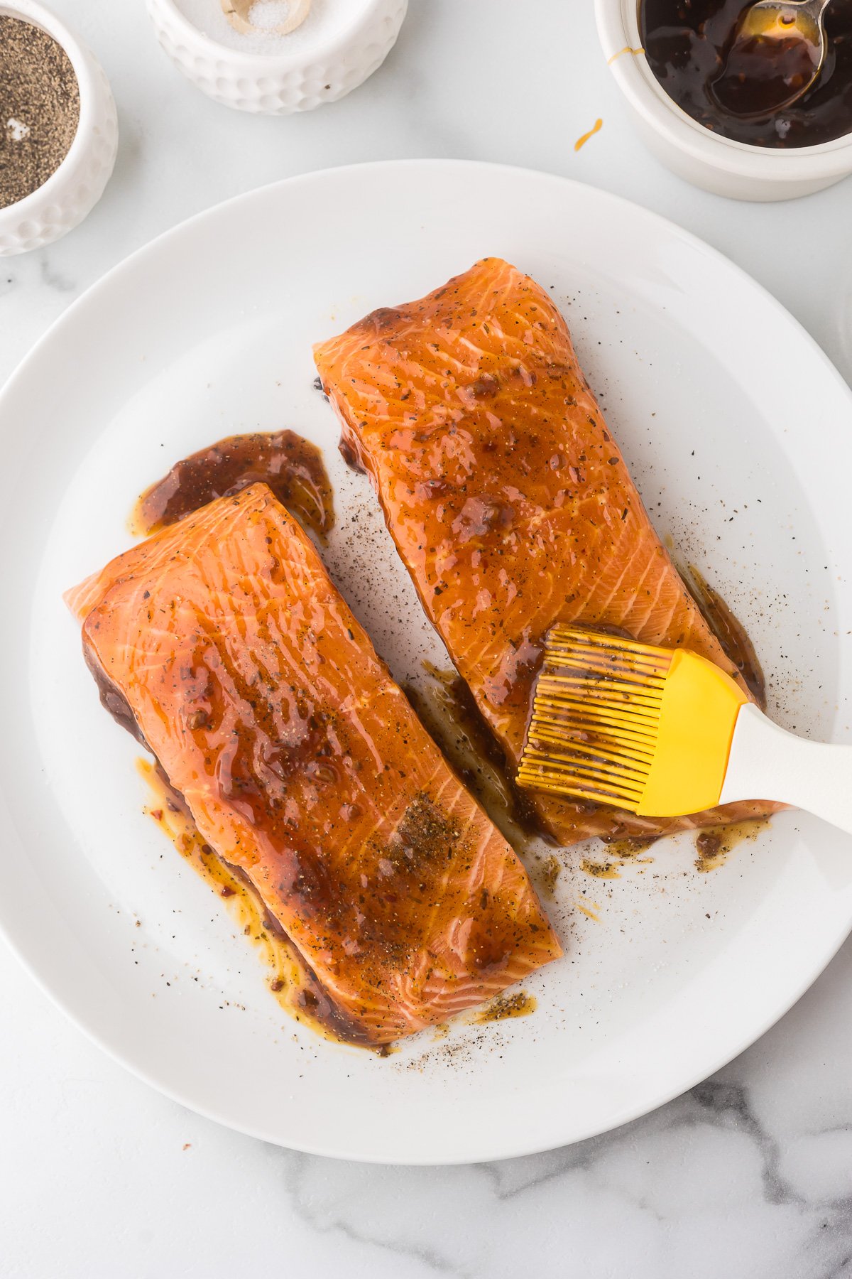 Salmon Fillets with teriyaki sauce being brushed on them.