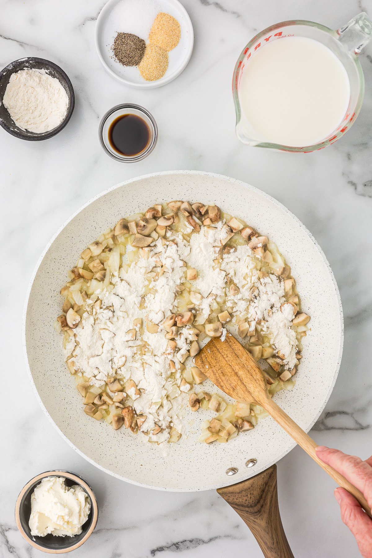 Flour being added to onion, mushrooms and butter after they have sauted.