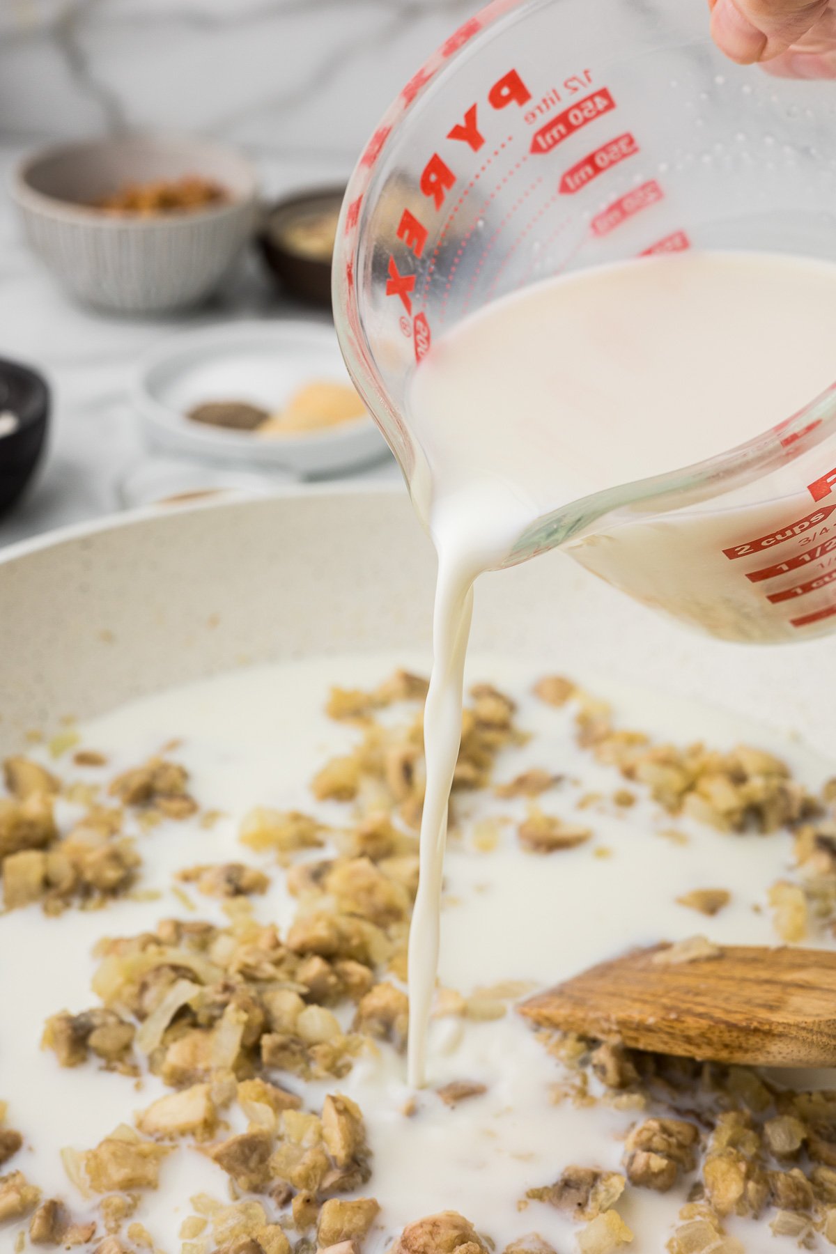 Milk being added into the sauce to make creamy green bean casserole with mushrooms.