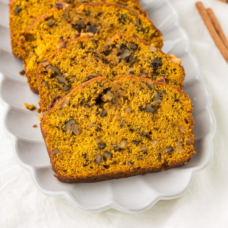 Pumpkin bread with walnuts sliced on a platter.