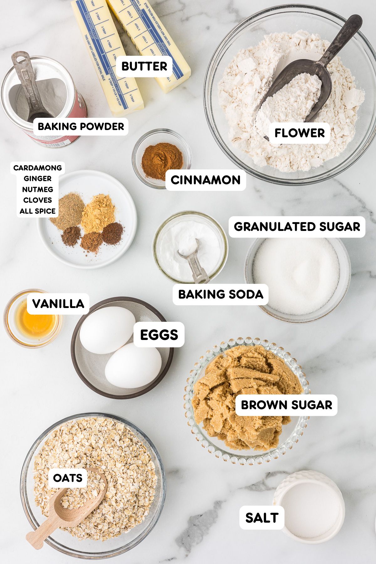 Bowls of rolled oats, flour, sugars, eggs, butter, vanilla, and chai spices for oatmeal cookies.