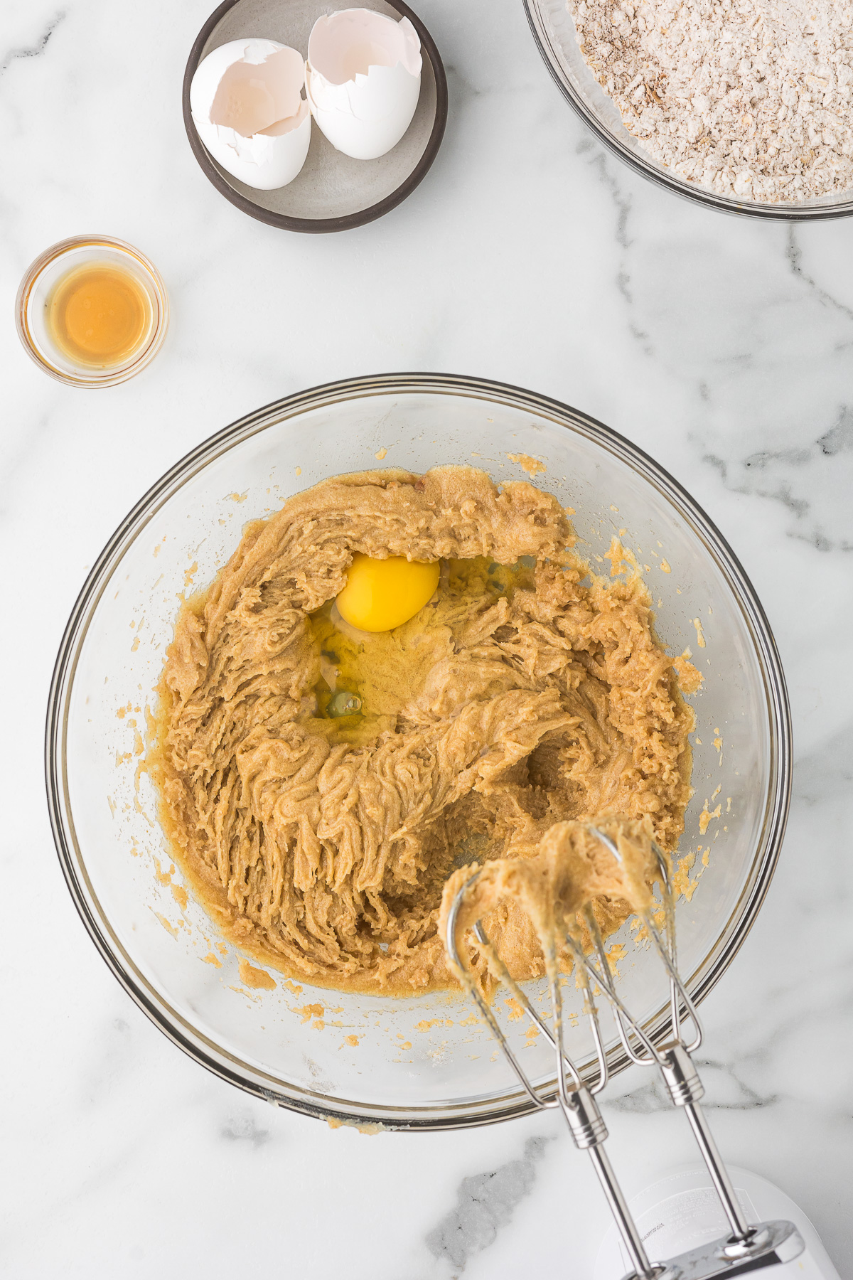 Browned butter mixed with sugars, with an egg being added to the bowl.