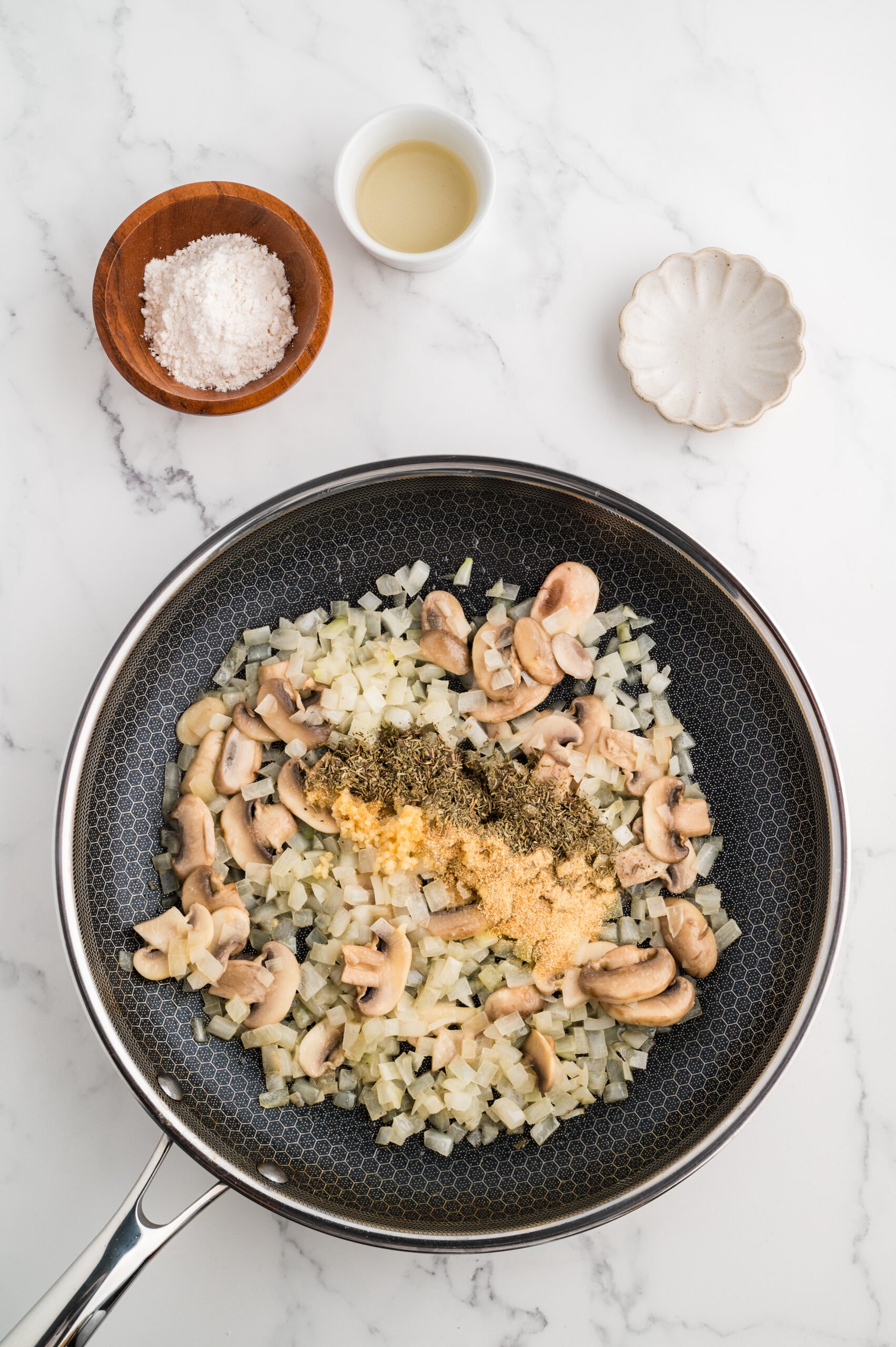 Onions and mushrooms with spices in a black skillet to make chicken stroganoff.
