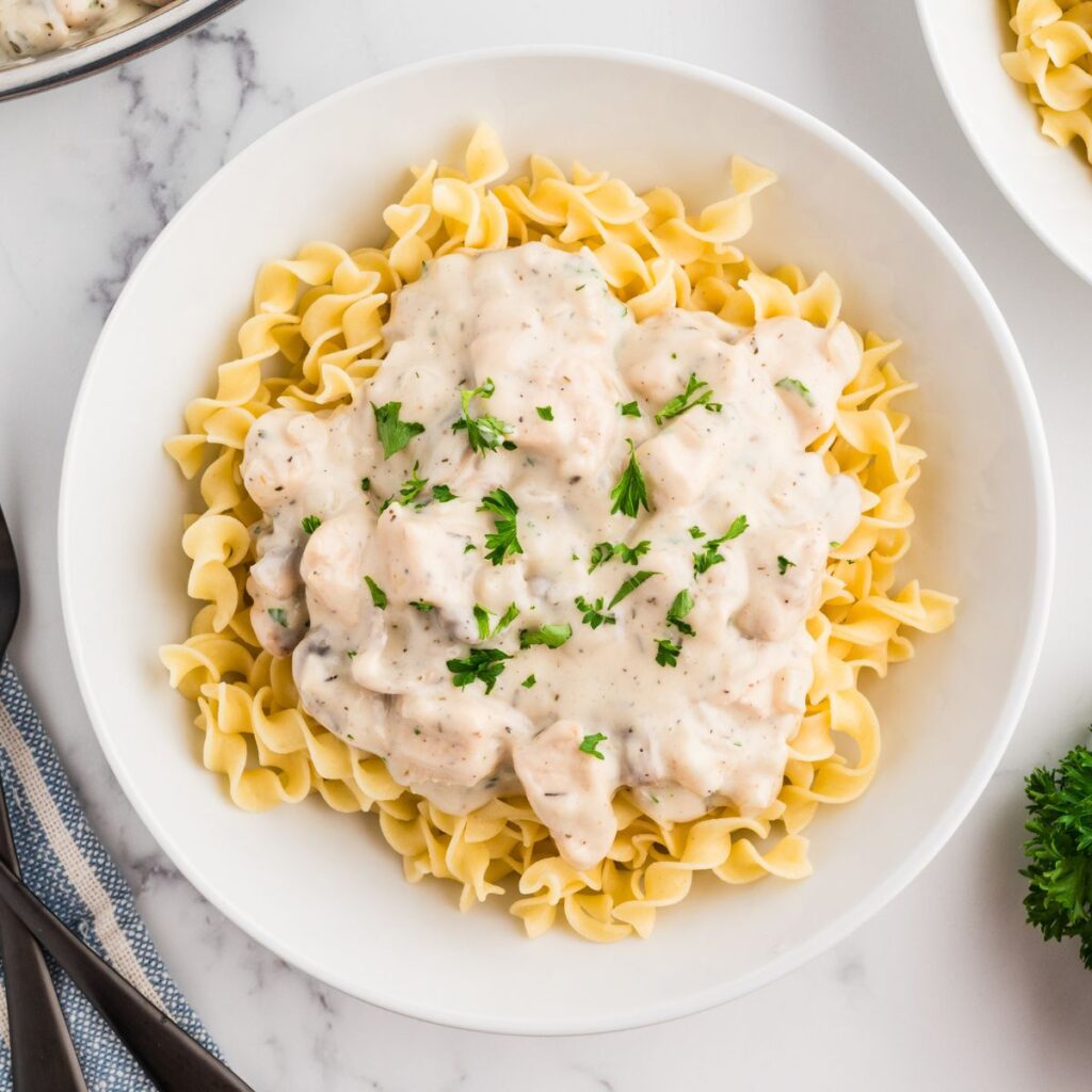 Easy Chicken Stroganoff with Mushrooms in a white bowl with parsley as garnish.
