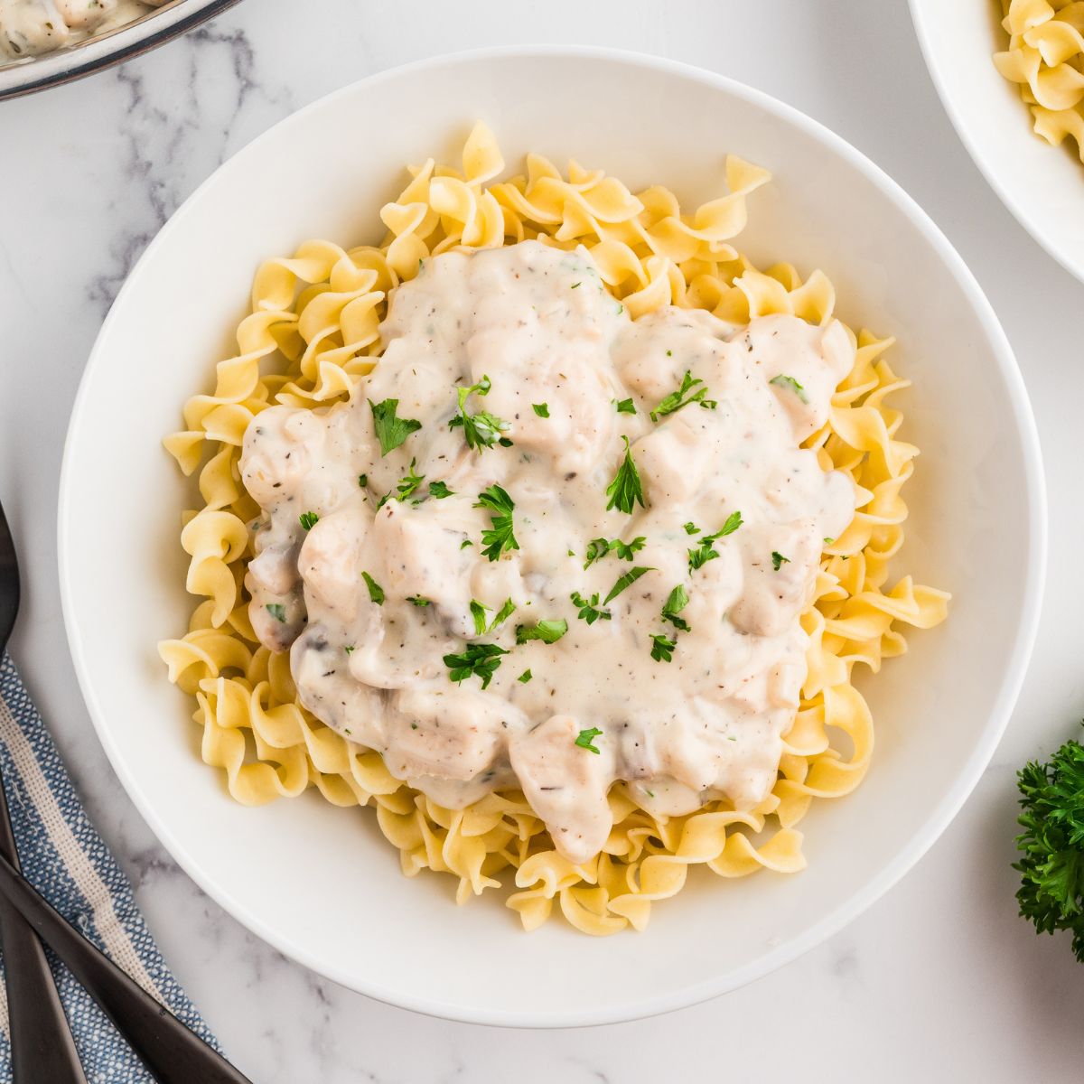 Easy Chicken Stroganoff with Mushrooms in a white bowl with parsley as garnish.