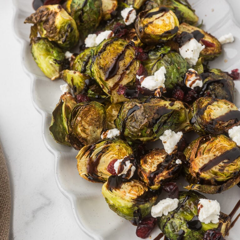 Air Fryer Brussels sprouts on a platter with balsamic, goat cheese and craisins.