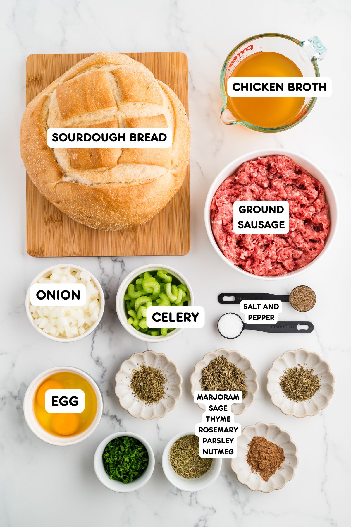 Ingredients for sourdough sausage stuffing including cubed sourdough bread, ground sage pork sausage, celery, onion, eggs, chicken broth, dried herbs, nutmeg, and fresh parsley.