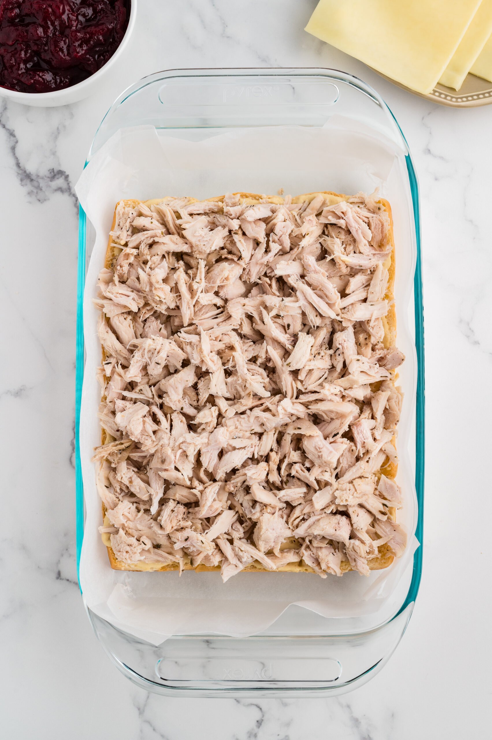 Baking dish filled with the bottom rolls topped with a full, even layer of shredded turkey.