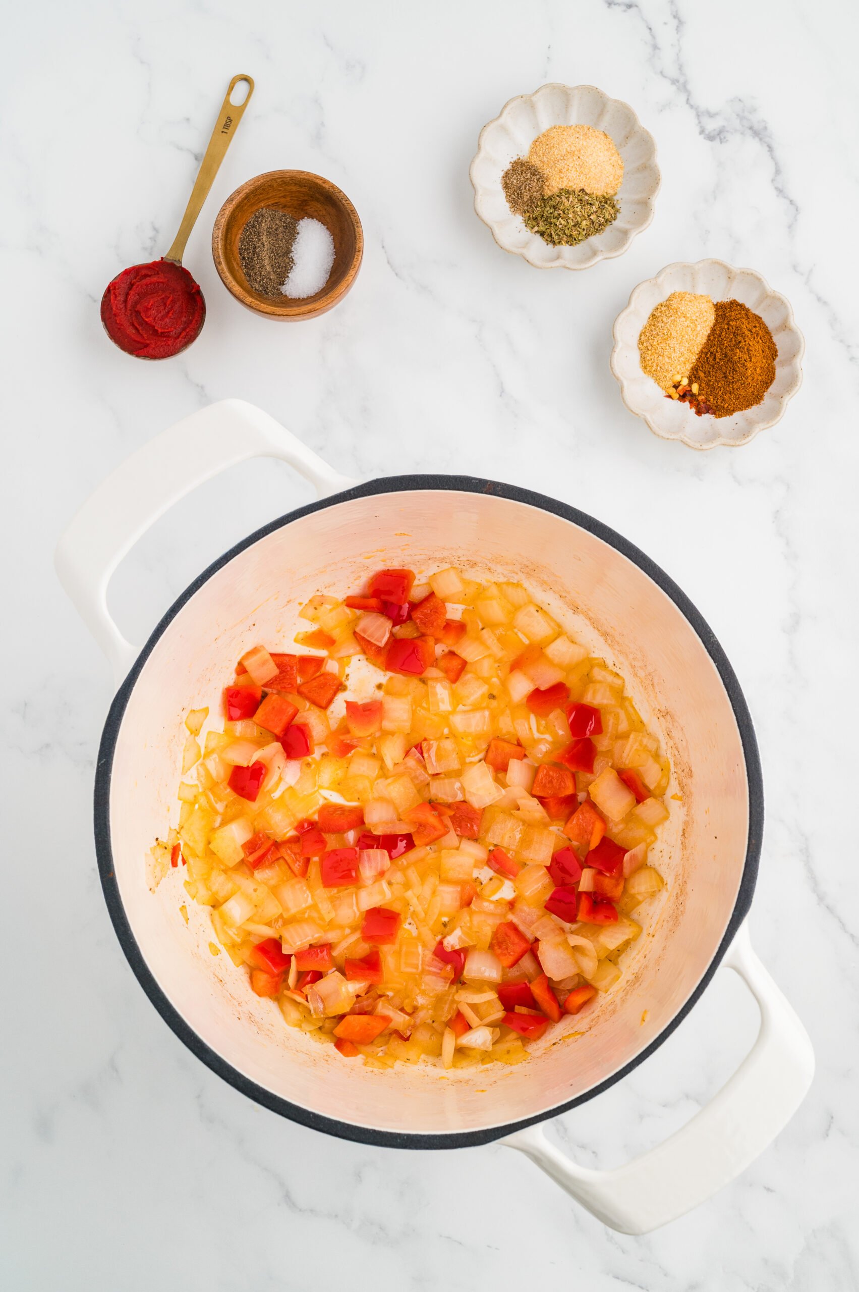 Diced onion and red bell pepper sautéing in a pot for cabbage roll soup.