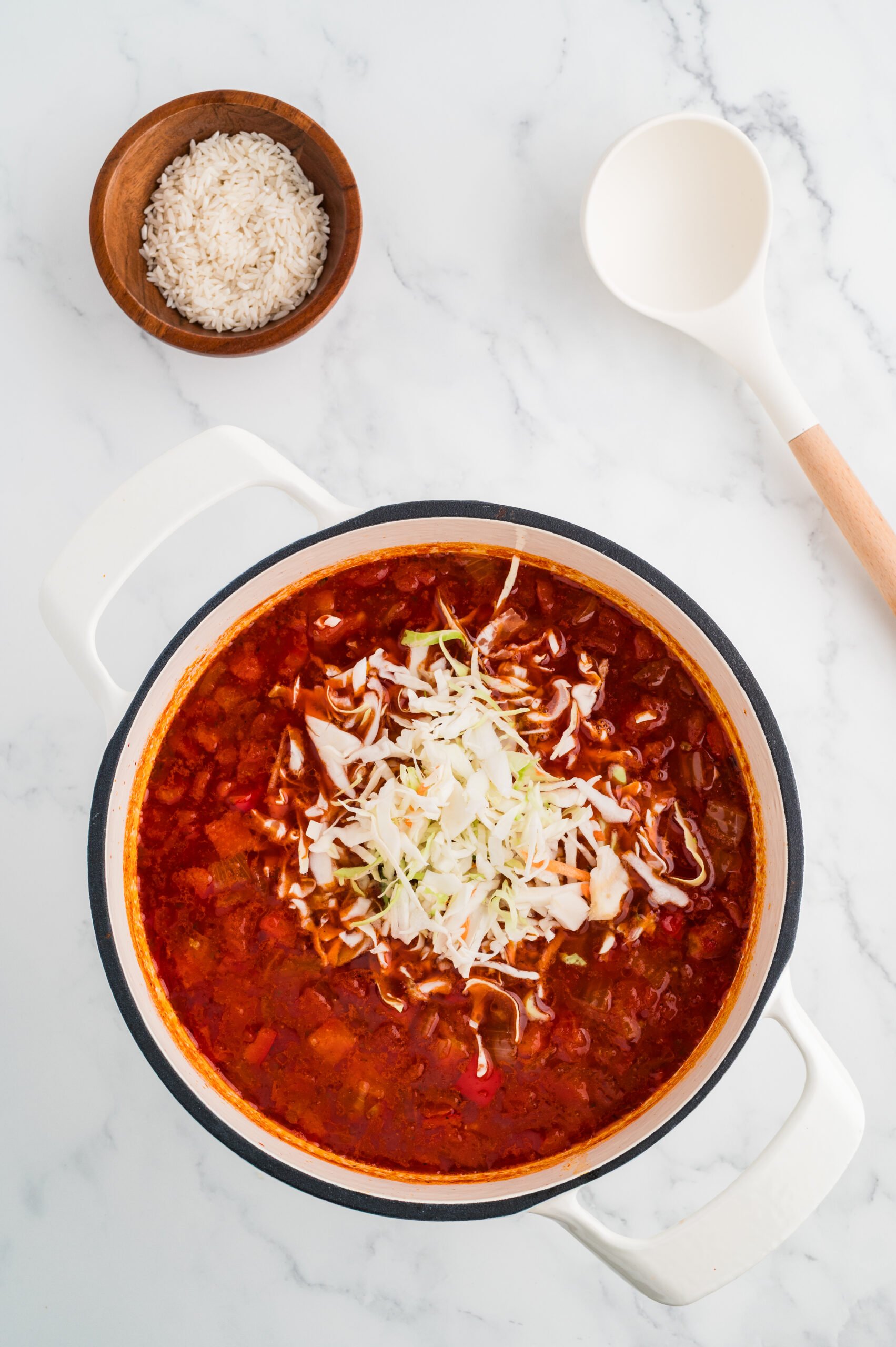 Shredded cabbage added to simmering cabbage roll soup.