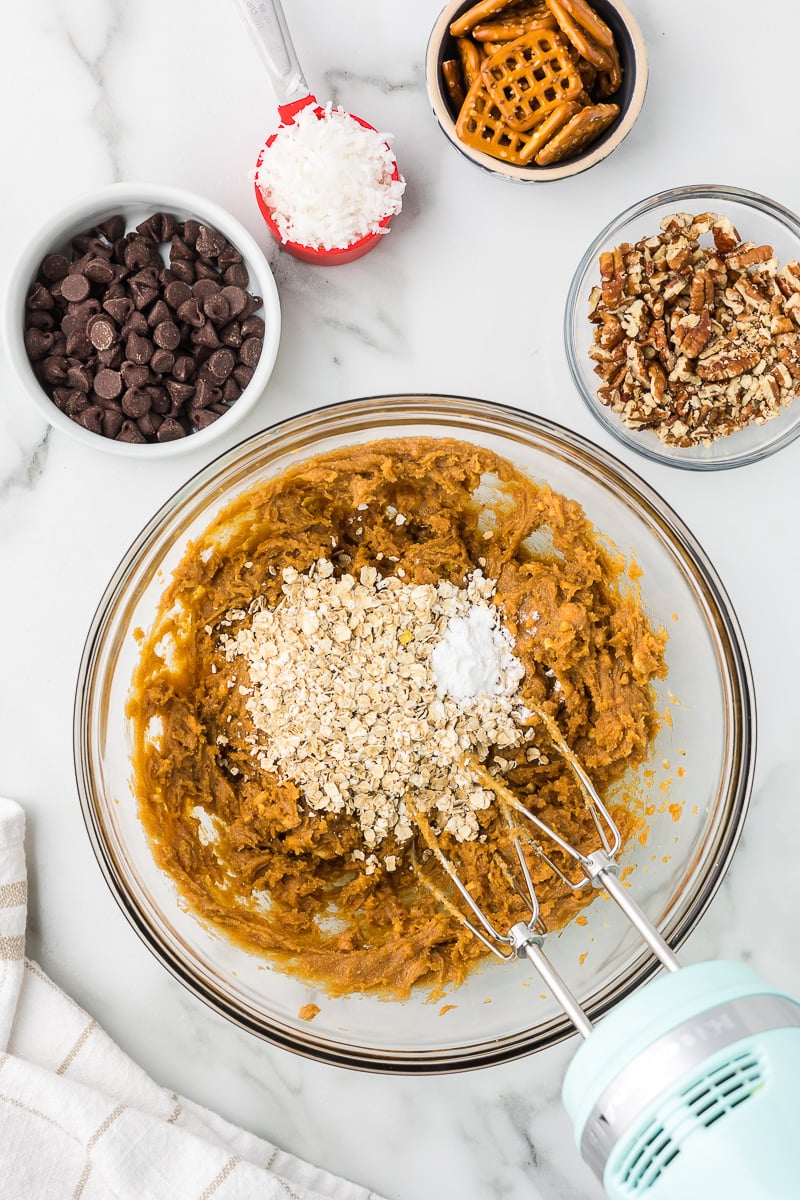 Peanut butter breakfast cookie dough being mixed in a glass bowl with oats and baking powder