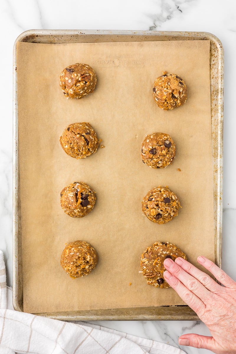 Peanut butter breakfast cookie dough balls arranged on a parchment-lined baking sheet before baking.