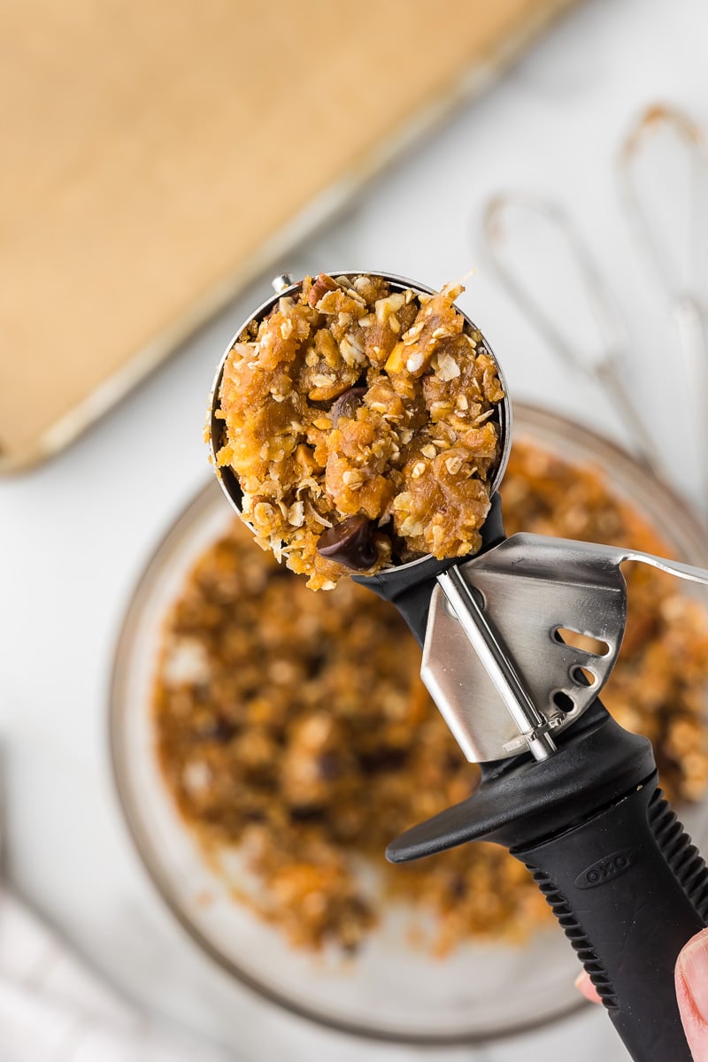 Scooping peanut butter breakfast cookie dough with oats, chocolate chips, and pretzels.