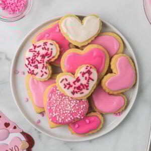 Decorated cut-out sugar cookies on a white plate stacked on one another.