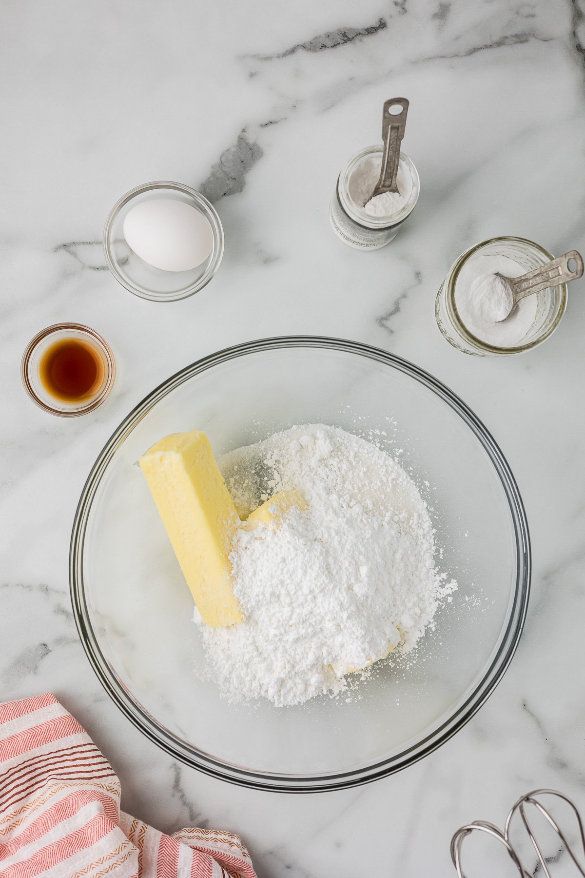 Butter and powdered sugar in a glass bowl ready to be mixed for cut out sugar cookie dough.