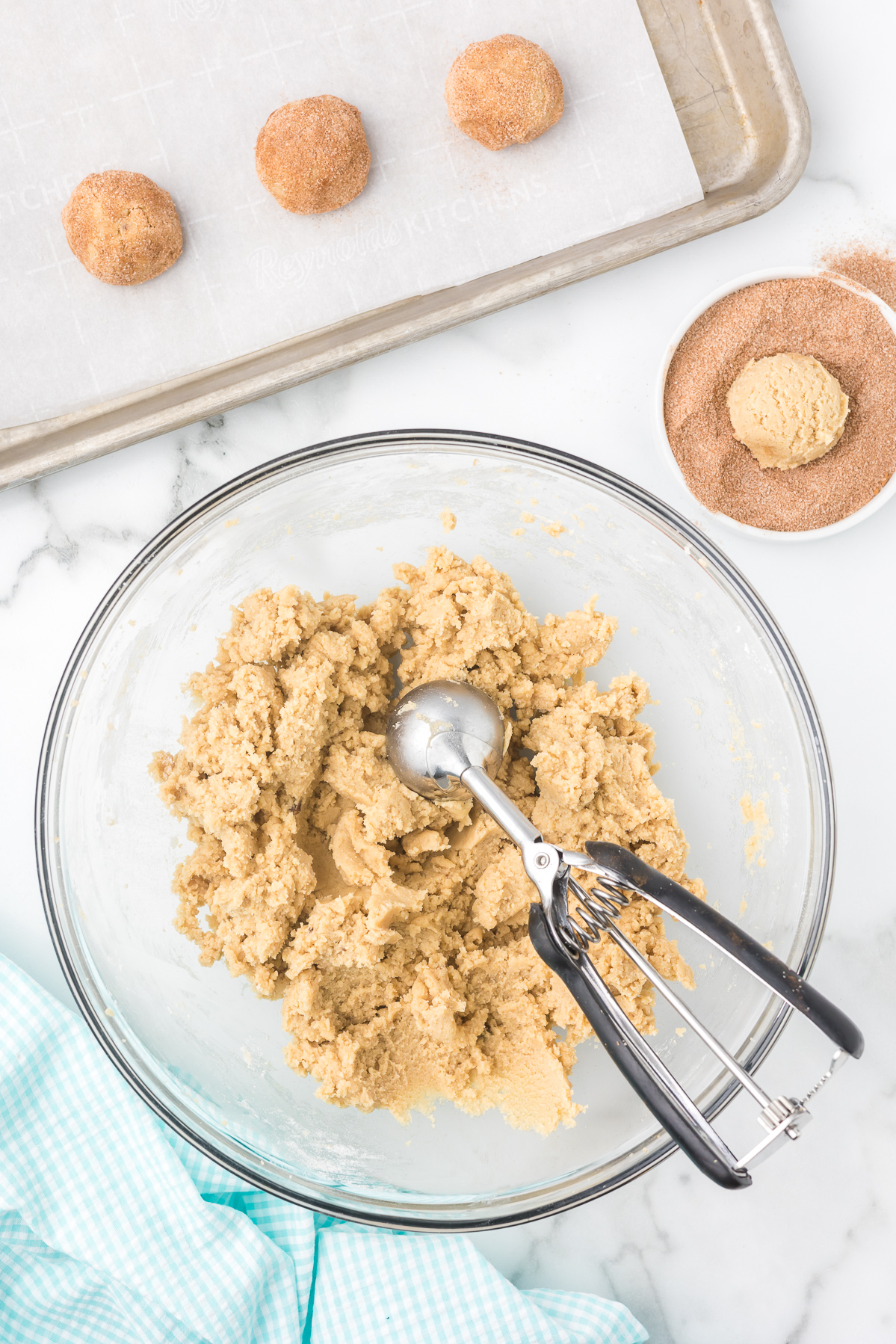 Scooping cinnamon sugar cookie dough and rolling in cinnamon sugar before baking.