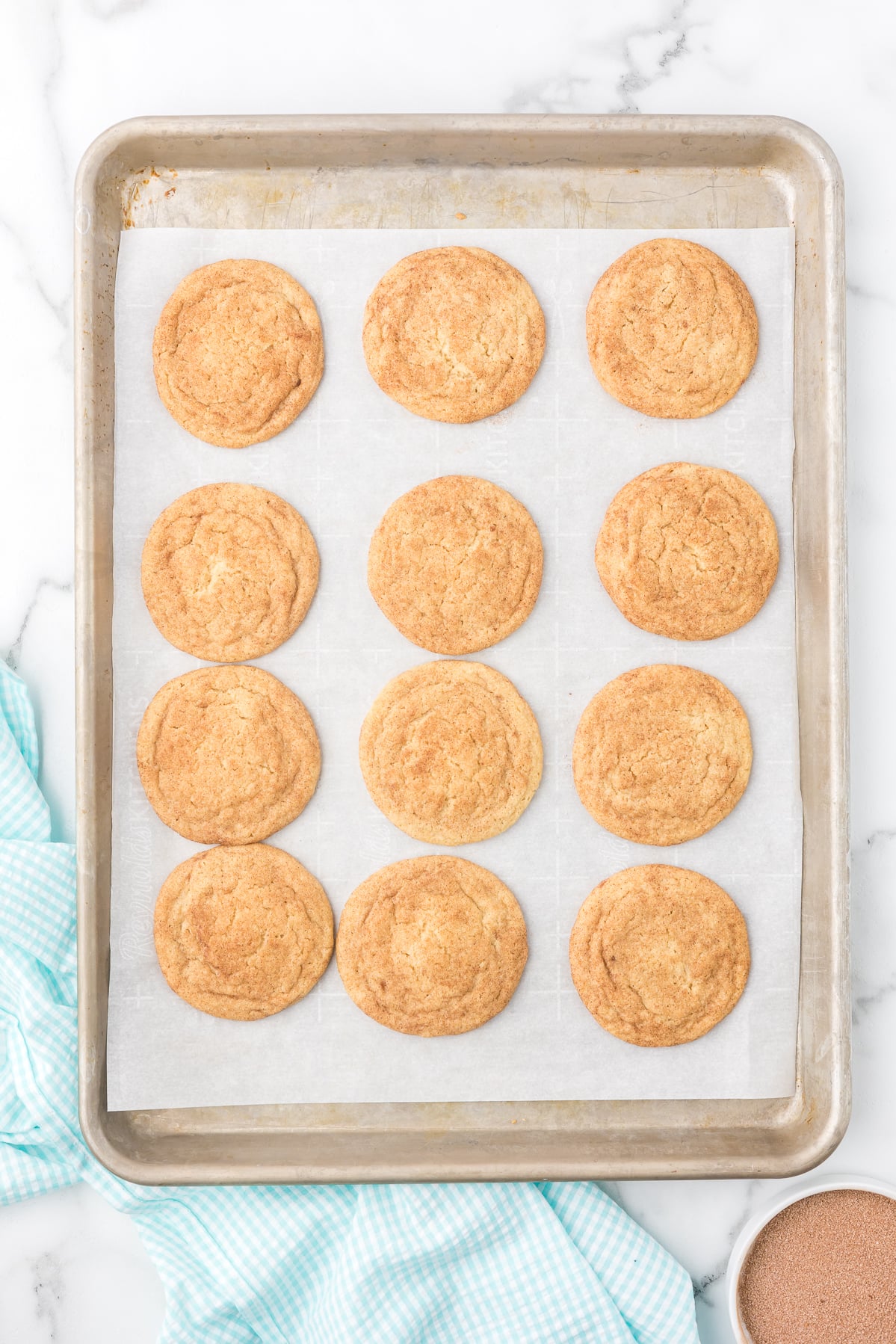 Soft baked cinnamon sugar cookies on a sheet pan, golden and ready to cool.
