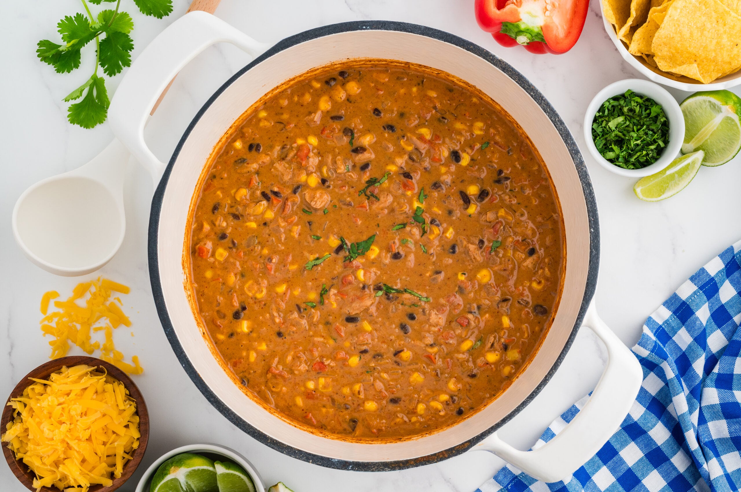 One pot creamy taco chicken soup with chicken, black beans, corn, and rice topped with cilantro in a large Dutch oven.