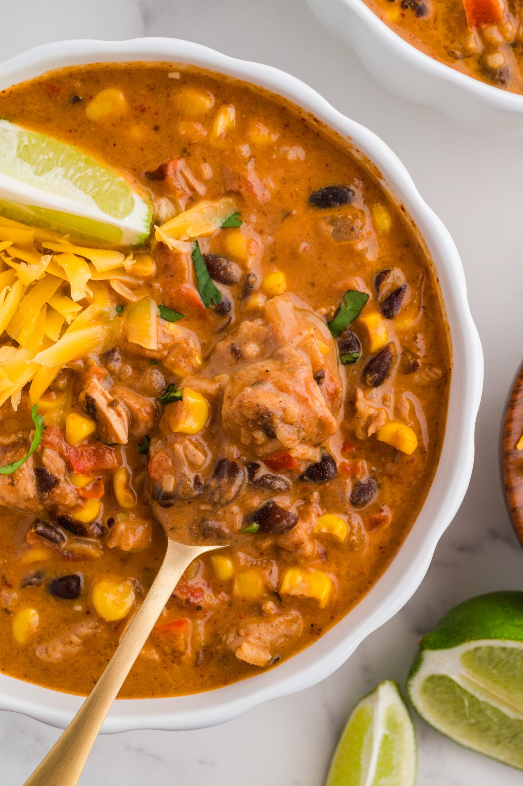 Taco Chicken soup in a bowl with lime and cheddar cheese.