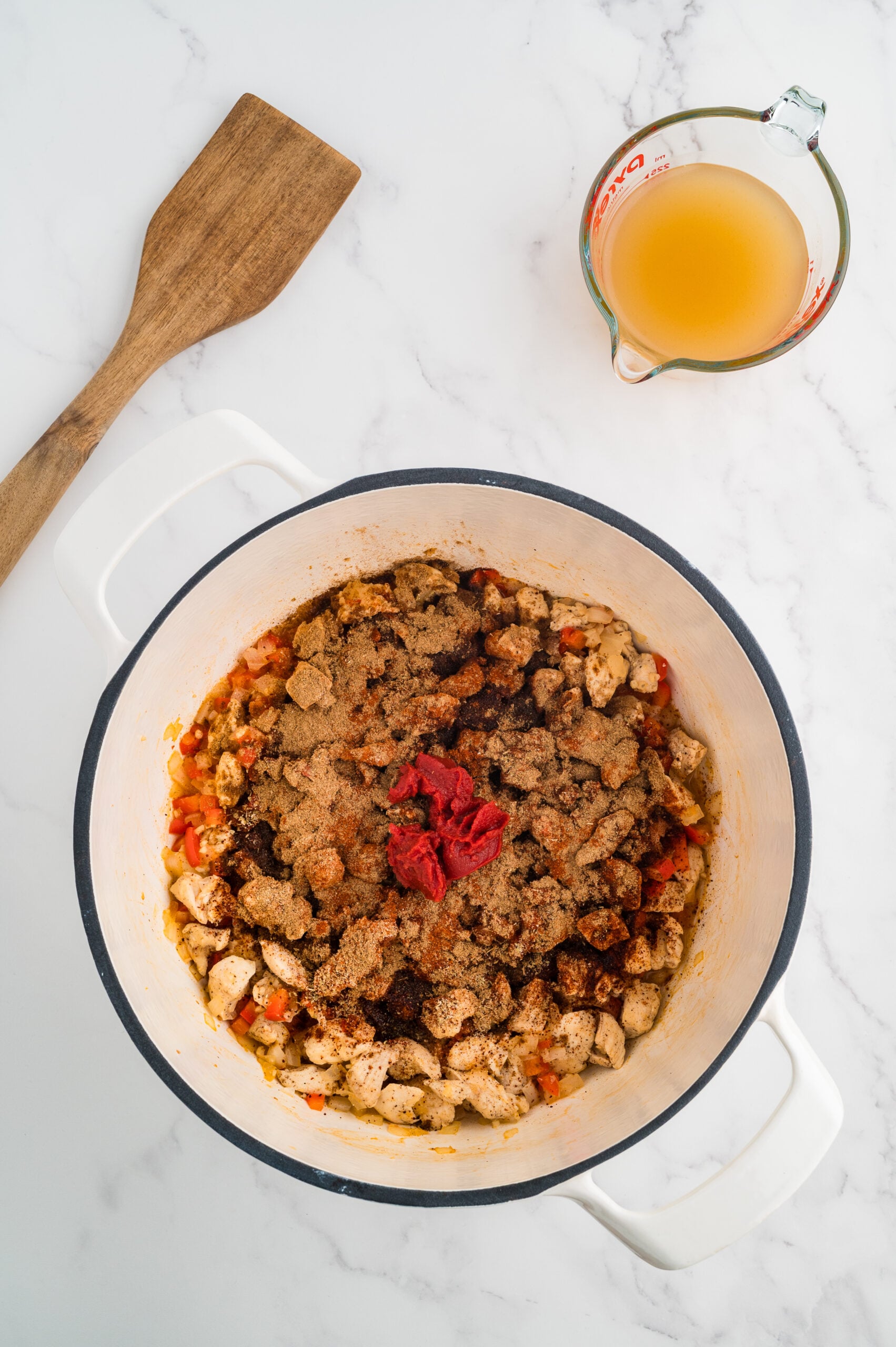 Chicken, vegetables, tomato paste, and spices added to the pot for taco chicken soup.