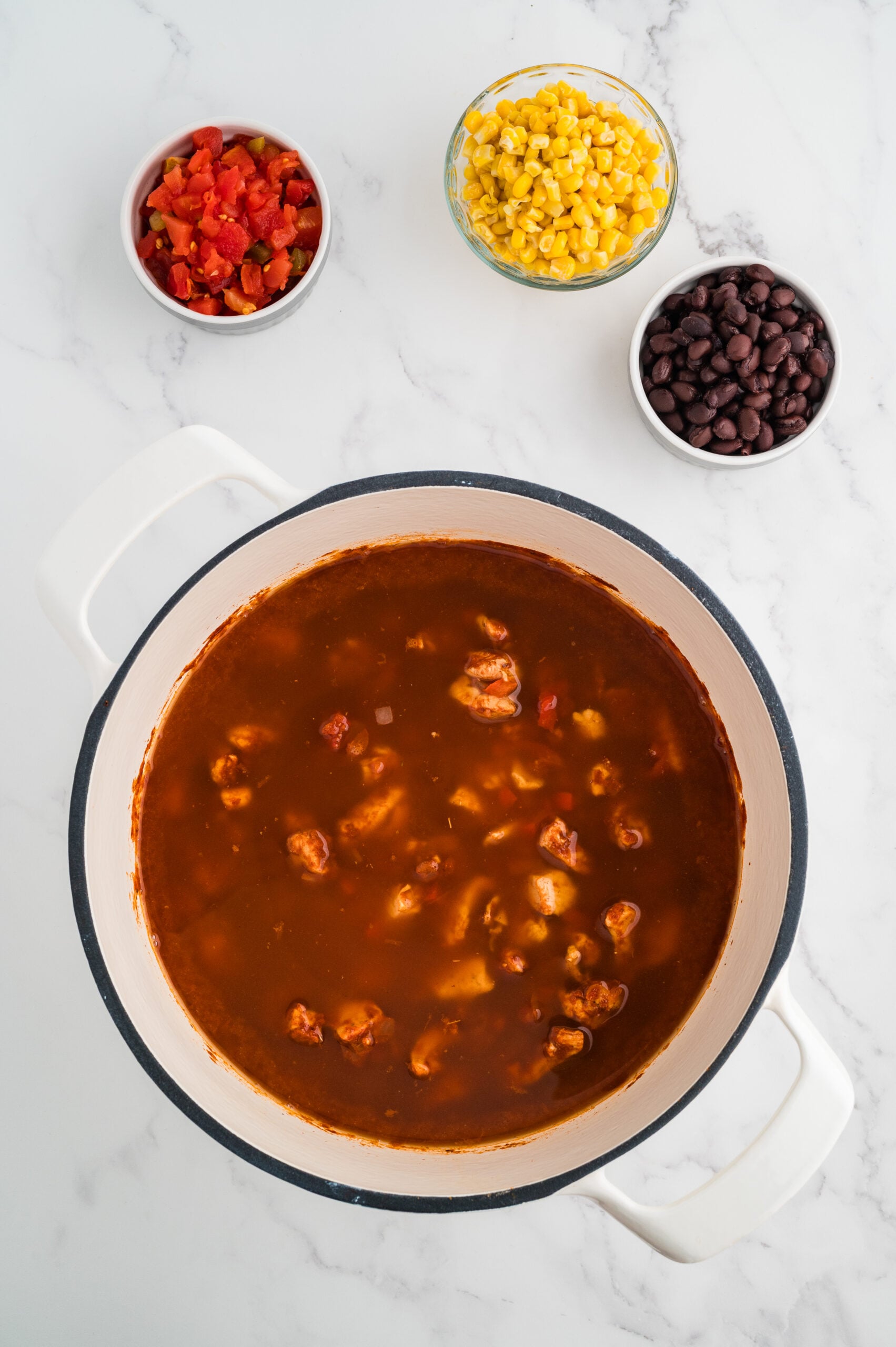 Chicken broth added to seasoned chicken mixture in pot for taco chicken soup.