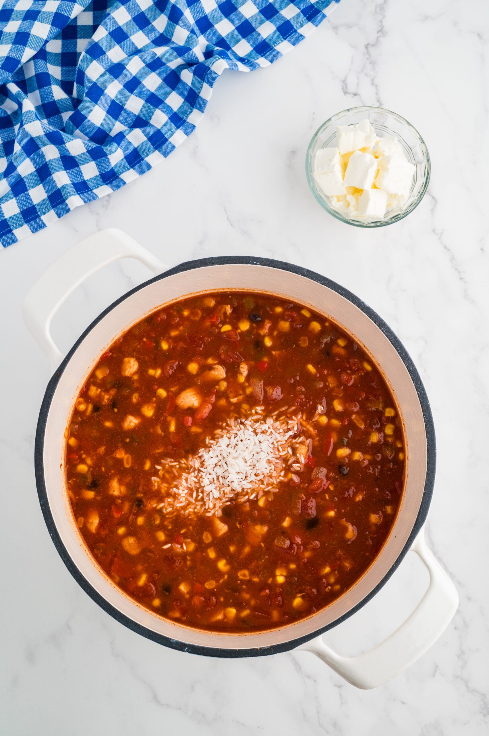 Rice added to simmering taco chicken soup in a large pot.