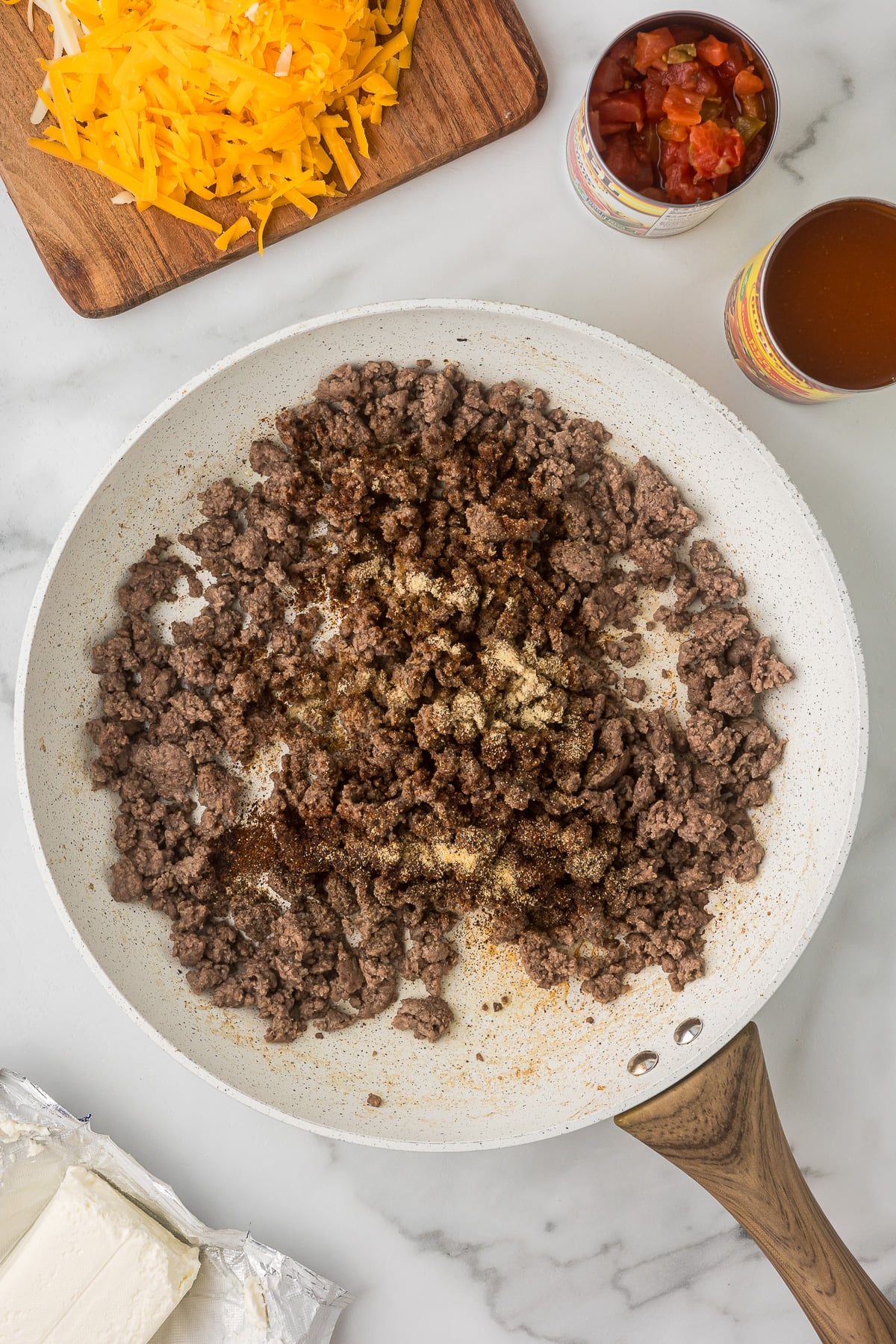 Ground beef cooking in a skillet with chili powder, garlic powder, and onion powder for Mexican mac and cheese.