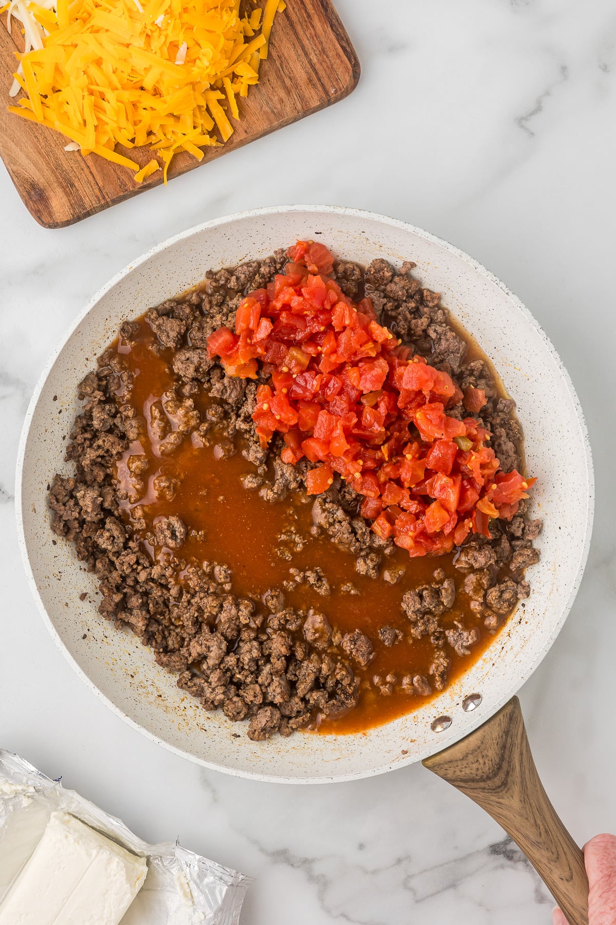 Ground beef with enchilada sauce and Rotel added in skillet for creamy Mexican mac and cheese.
