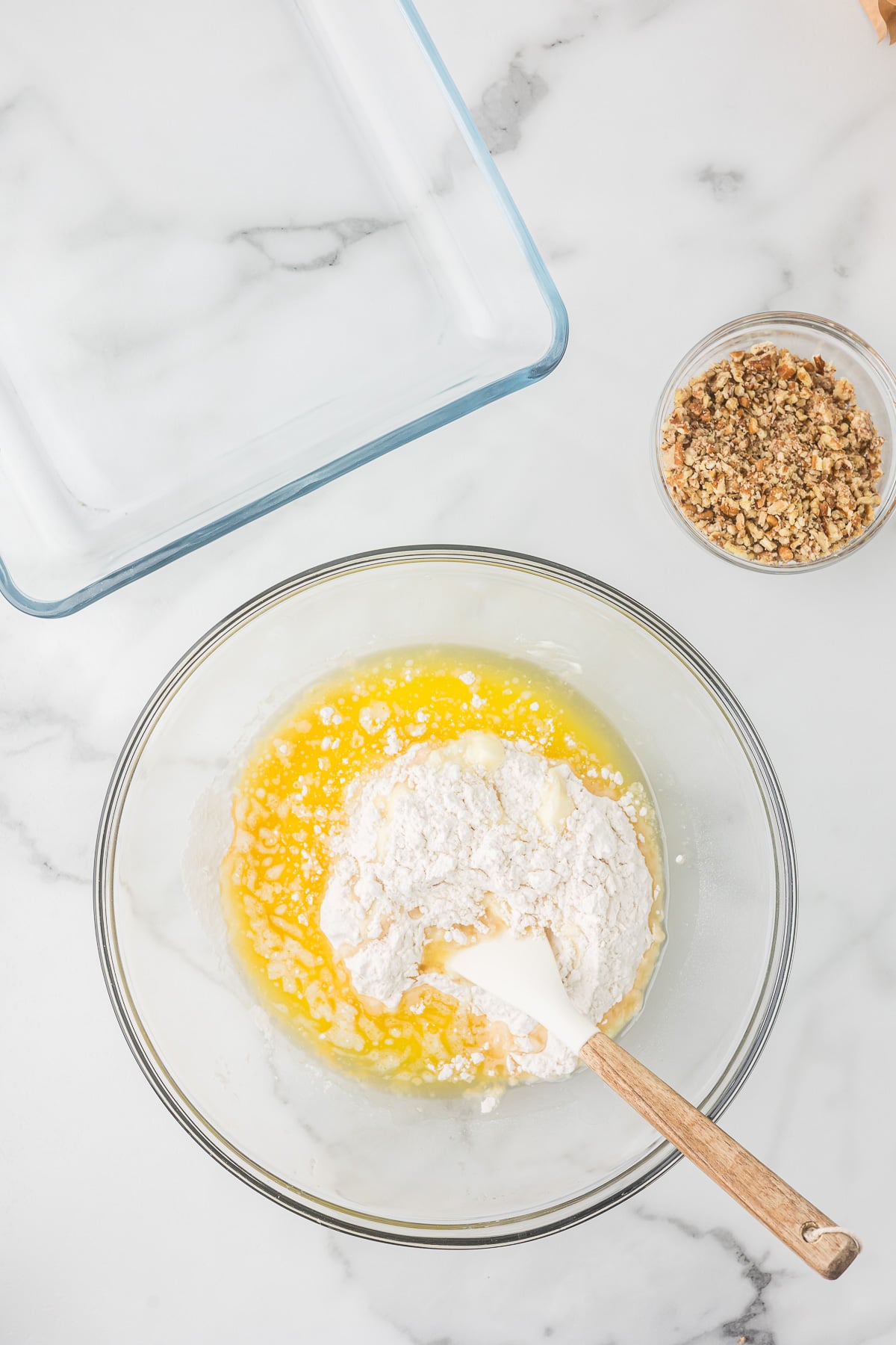 Melted butter and flour being mixed in a bowl to make the pecan crust for Chocolate Delight.