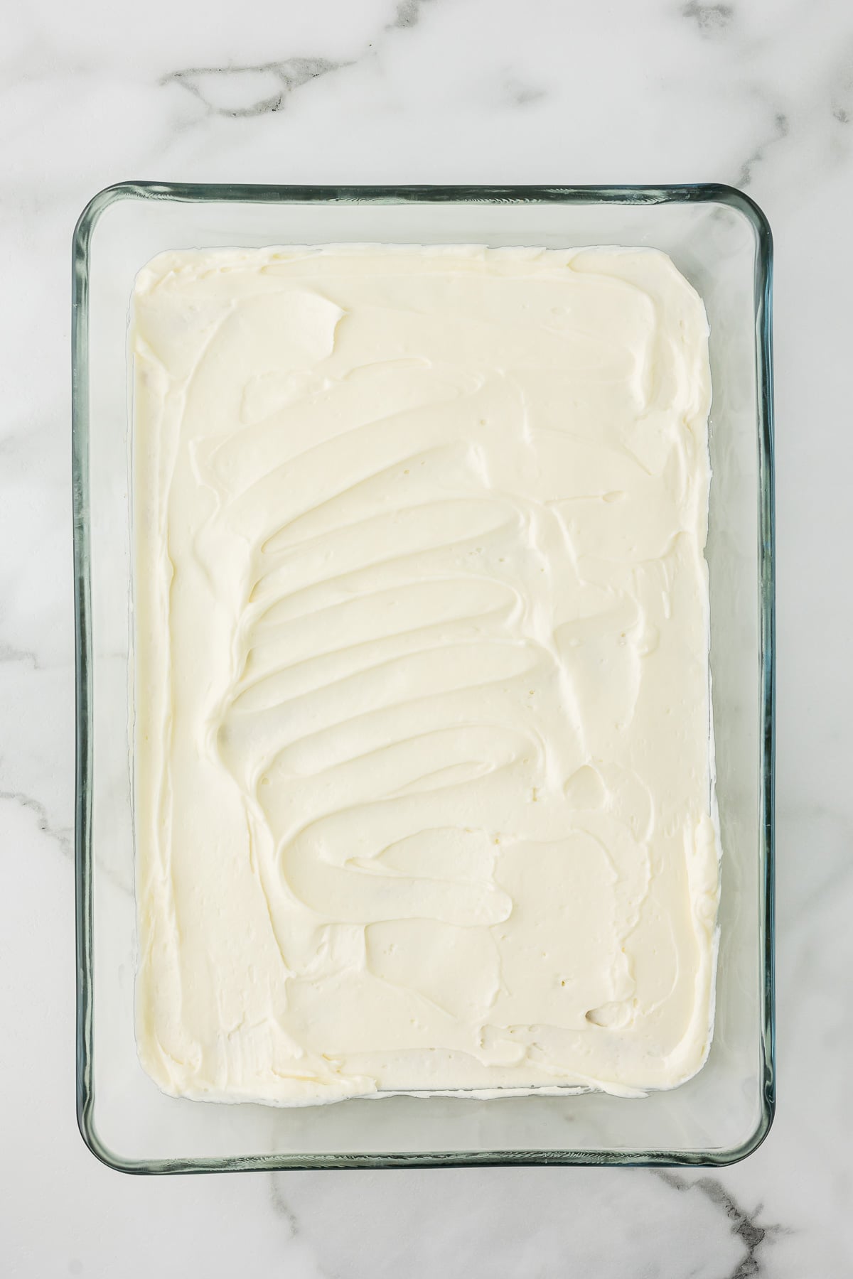 Cream cheese layer spread evenly over the cooled pecan crust for Chocolate Delight.