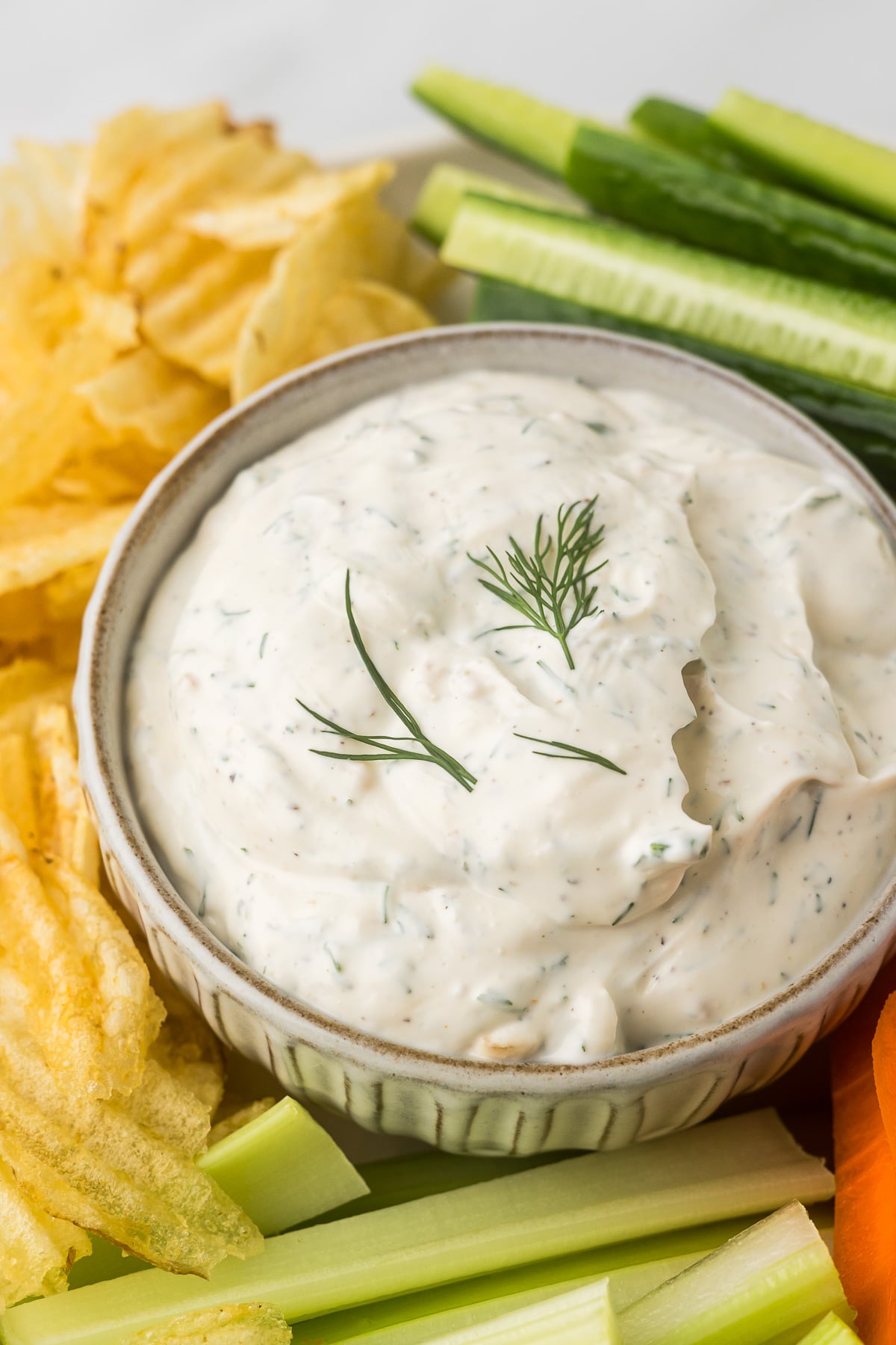 Dill dip in a bowl with chips, celery, carrots and cucumbers.