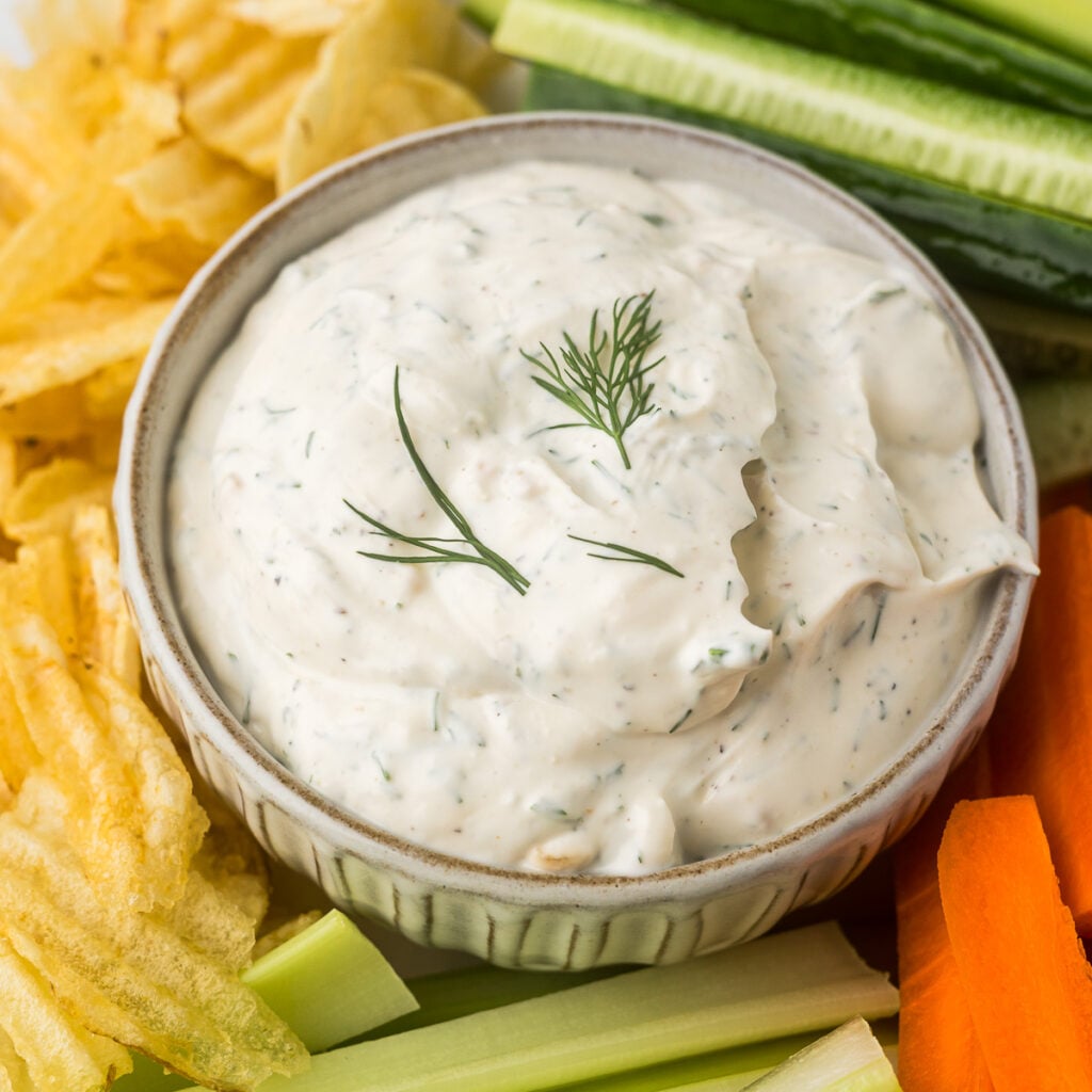 Creamy Dill Dip in a bowl with veggies and potatoes chips.
