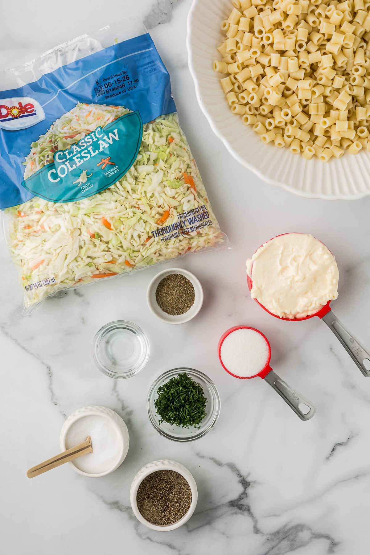 Ingredients to make a creamy pasta salad with coleslaw, mayo, spices, sugar and pasta.