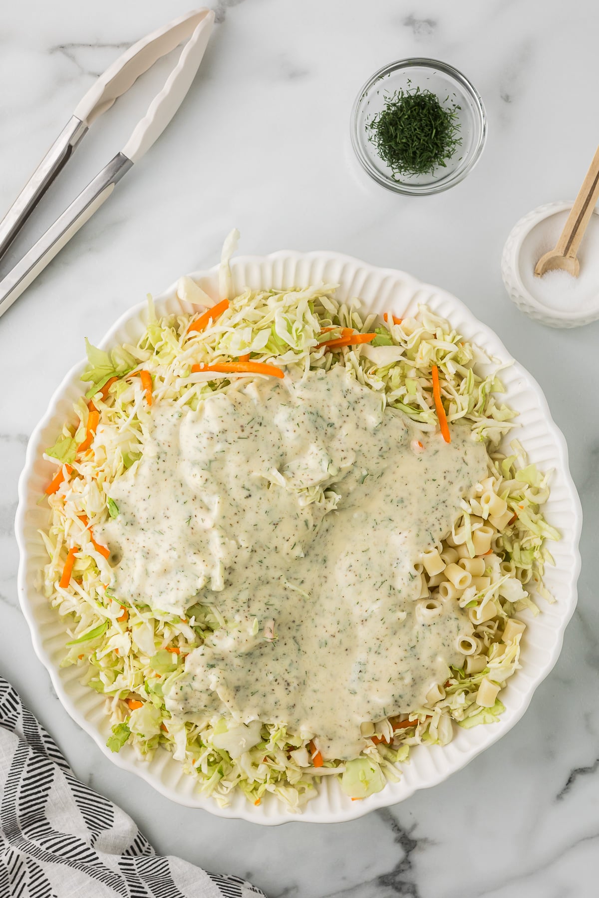 Coleslaw mix, pasta and dressing before mixing it up in a white bowl.