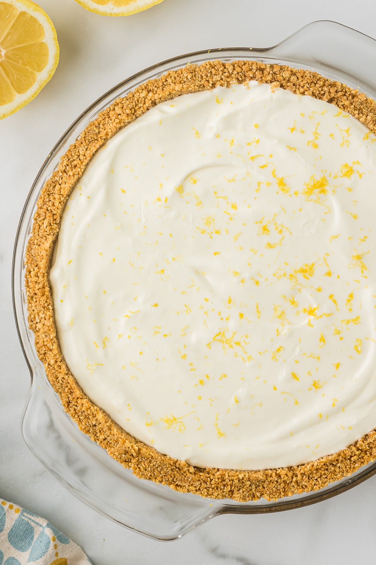 Lemon Pie in a clear pie pan with a lemon on the side.