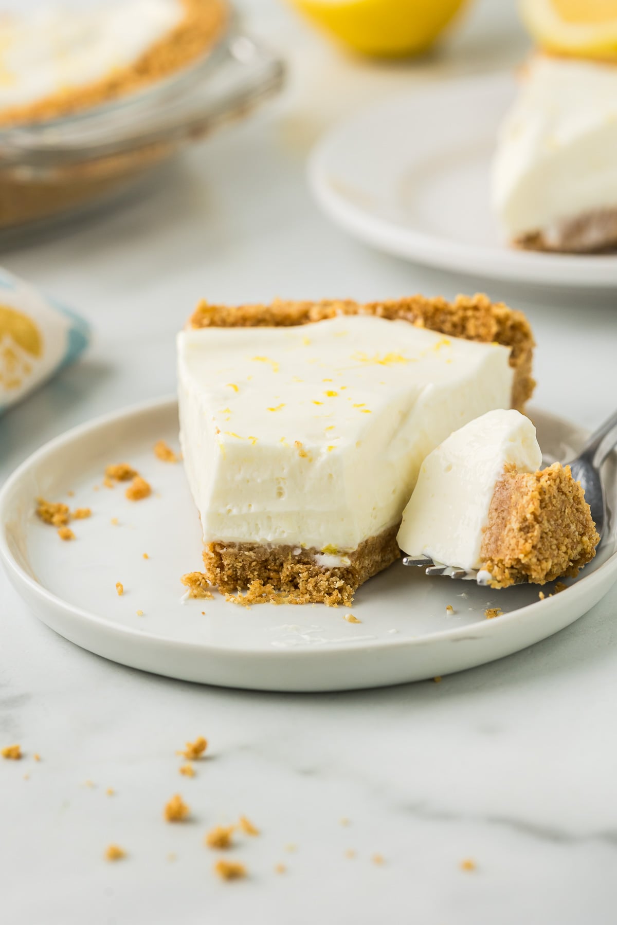 A piece of No Bake Lemon Pie with a bite removed on a small white plate.