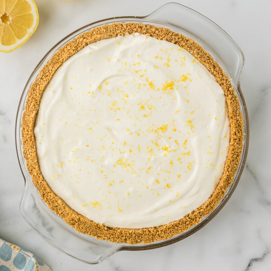No Bake Lemon Pie with a thick homemade graham cracker crust in a white pie plate.