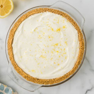 No Bake Lemon Pie with a thick homemade graham cracker crust in a white pie plate.