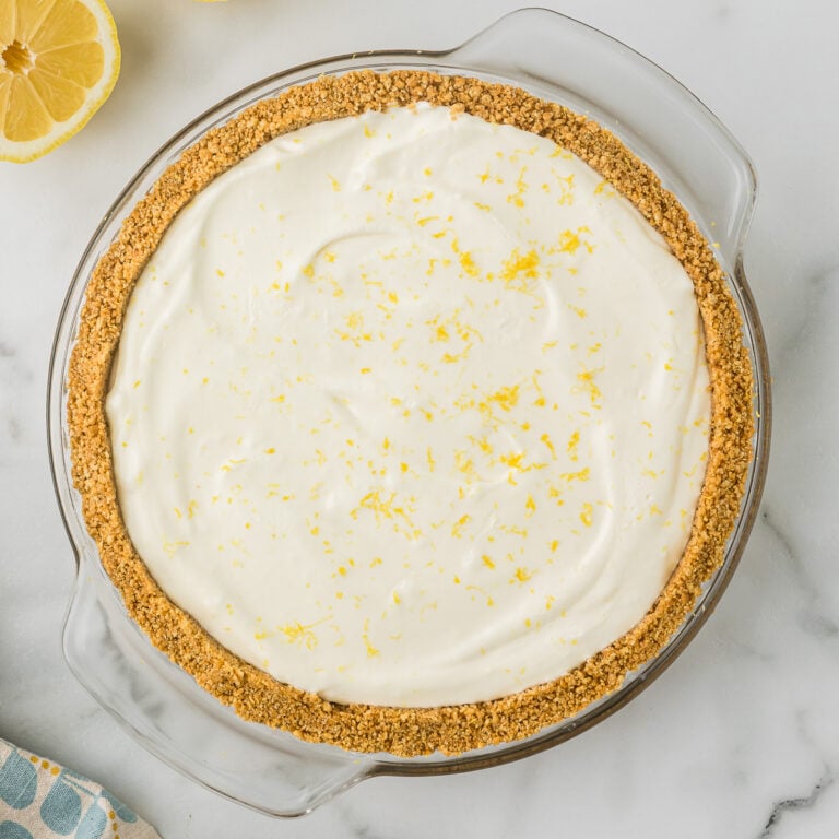 No Bake Lemon Pie with a thick homemade graham cracker crust in a white pie plate.