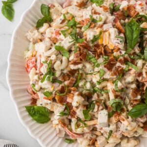 Close-up of homemade BLT Chicken Pasta Salad with chicken, bacon, cheddar cheese, tomatoes, fresh basil, and creamy ranch dressing.