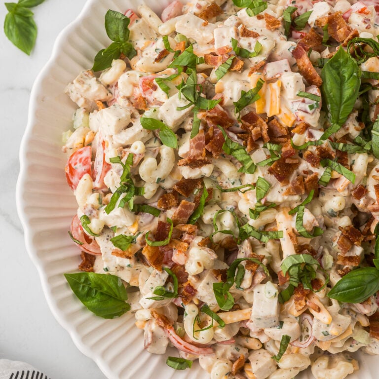 Close-up of homemade BLT Chicken Pasta Salad with chicken, bacon, cheddar cheese, tomatoes, fresh basil, and creamy ranch dressing.