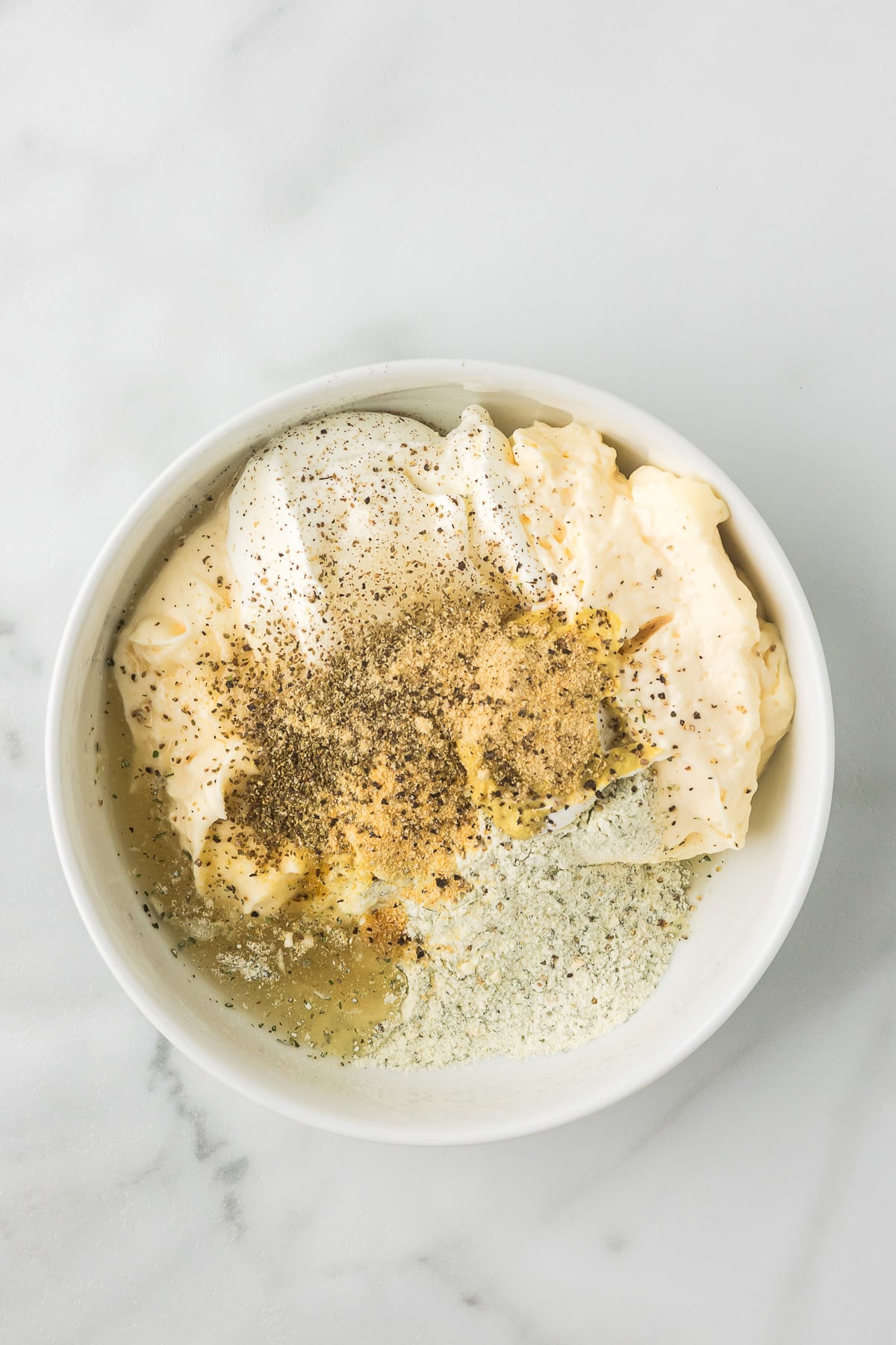 Mayonnaise, sour cream, ranch seasoning, Dijon mustard, vinegar, and spices combined to make the creamy dressing for BLT Chicken Pasta Salad.