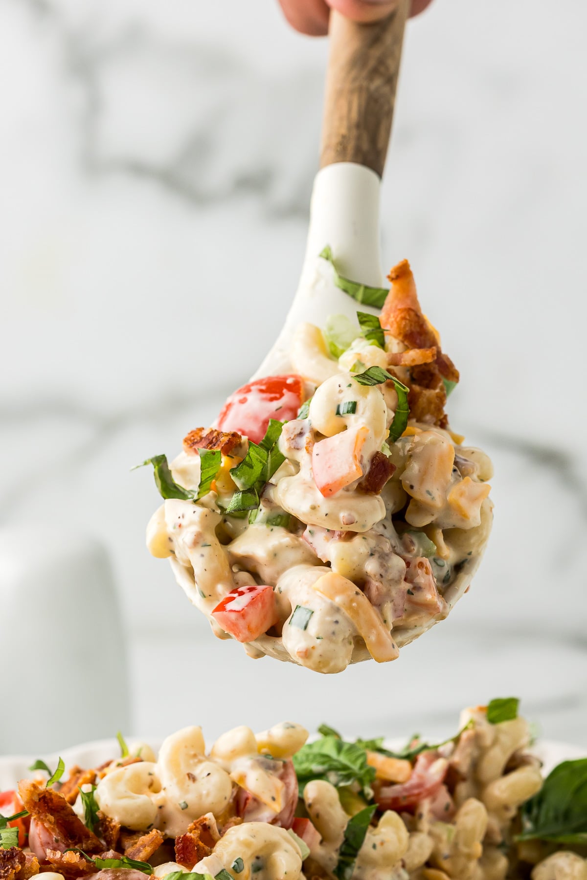 A spoonful of creamy BLT Chicken Pasta Salad with chicken, bacon, tomatoes, cheddar cheese, and elbow macaroni.